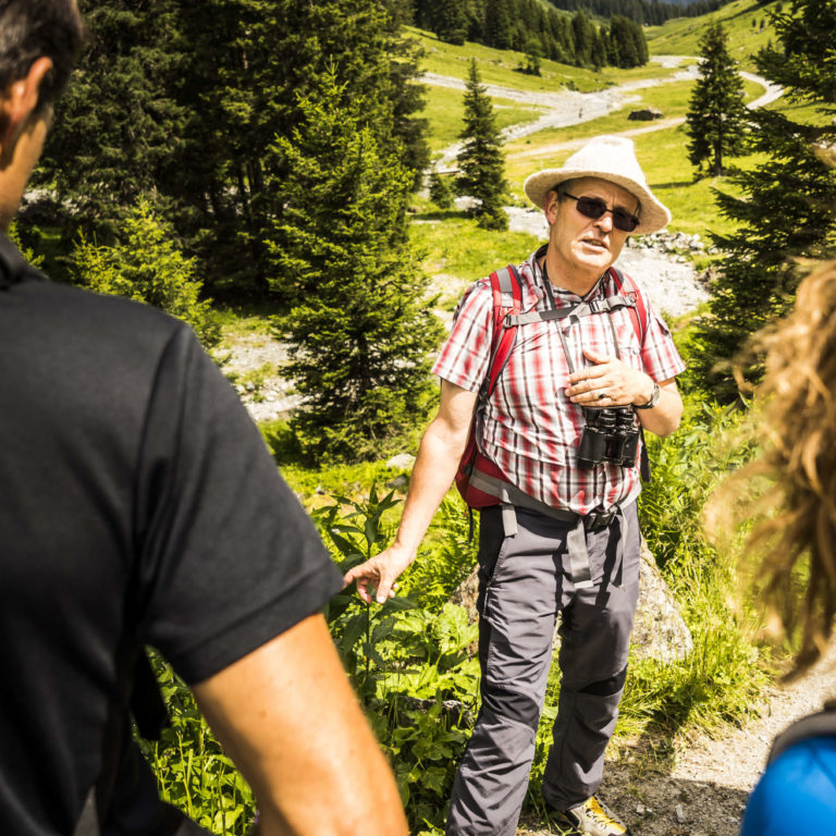 Ein Wanderführer erzählt Wanderern Wissenswertes auf der Wanderung.