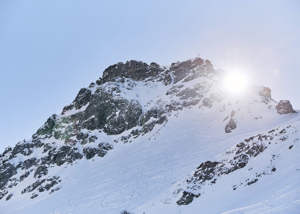 Schneebedeckte Kanzelwand, hinter dem Berg kommt die Sonne hervor