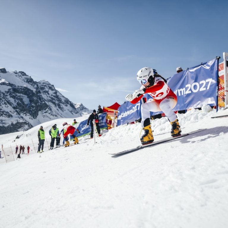 Eine WM-Teilnehmerin fährt mit dem Snowboard auf der Rennstrecke, am Rand stehen Zuseher.