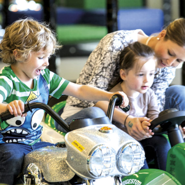 Zwei Kinder und eine Mutter fahren mit den Gokart in der Spielfabrik Dornbirn. 