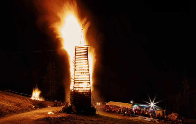 Der Funken in der Parzelle Kehlegg in Dornbirn im Vollbrand, rundherum Zuschauer:innen, die das traditionelle Funken-Abbrennen bestaunen