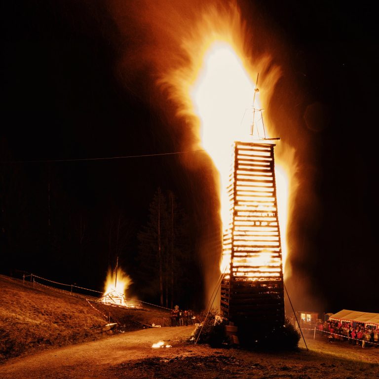 Der Funken in der Parzelle Kehlegg in Dornbirn im Vollbrand, rundherum Zuschauer:innen, die das traditionelle Funken-Abbrennen bestaunen