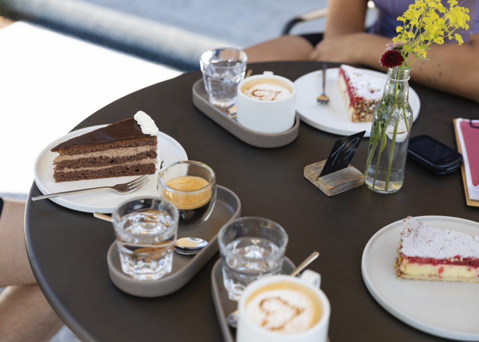 Kuchenstücke und Kaffee auf einem Tisch im Garten einer Bäckerei im Bregenzerwald in Vorarlberg.