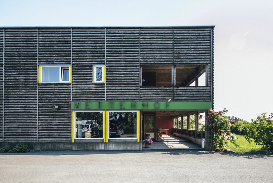 Man sieht ein Gebäude mit Holzfassade mit der Aufschrift 