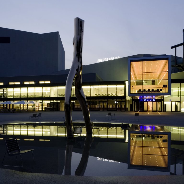 Das beleuchtete Festspiel- und Kongresshaus Bregenz bei Nacht, im Vordergrund das Kunstobjekt 