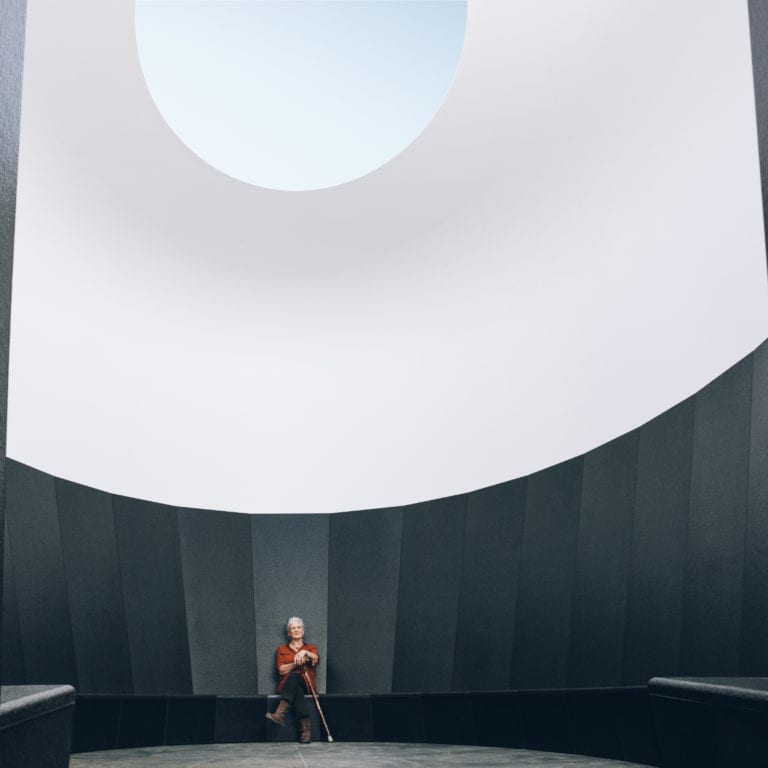 Eine Frau sitzt im Skyspace Lech und schaut zur Öffnung hinauf