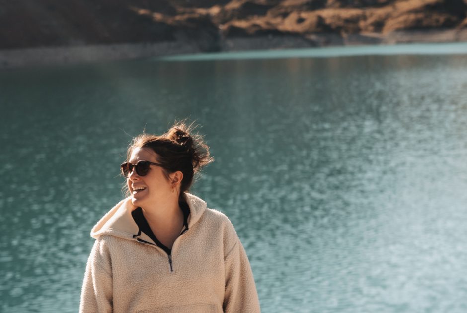 Laura Manao läuft lächelnd auf die Kamera zu. Im Hitergrund der grünschimmernde Lünersee un die schneebedeckten Gipfel der Berge