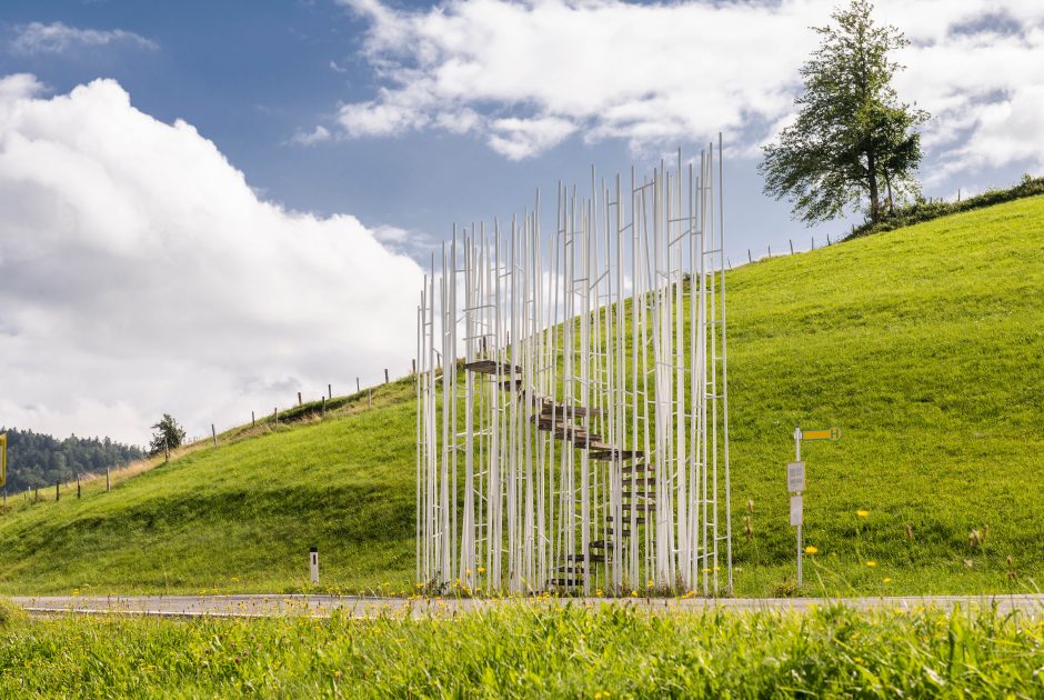 Die Bushaltestelle in Krumbach vom japanischen Architekt Sou Fujimotos. Ein „Wald“ aus wilden dünnen, weißen Stahlstangen. In dieser offenen Struktur windet sich eine Stiege in die Höhe. Die Bushaltestelle liegt an einer ruhigen Straße inmitten der grünenden Wiesen