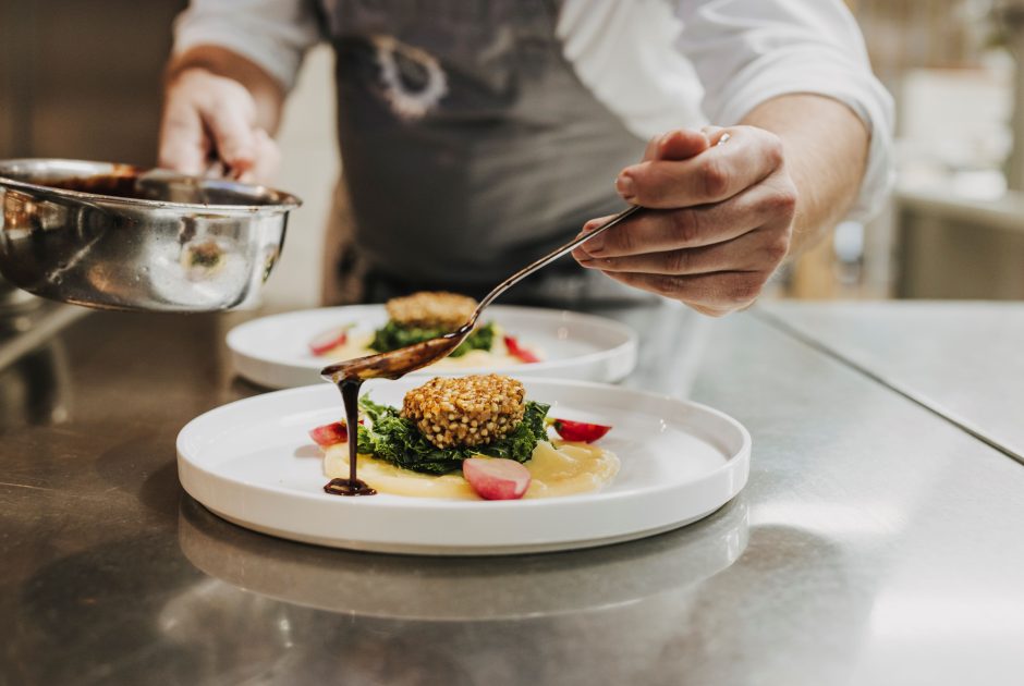 Koch richtet die Speise auf dem Teller an, im Chesa Valisa im Kleinwalsertal