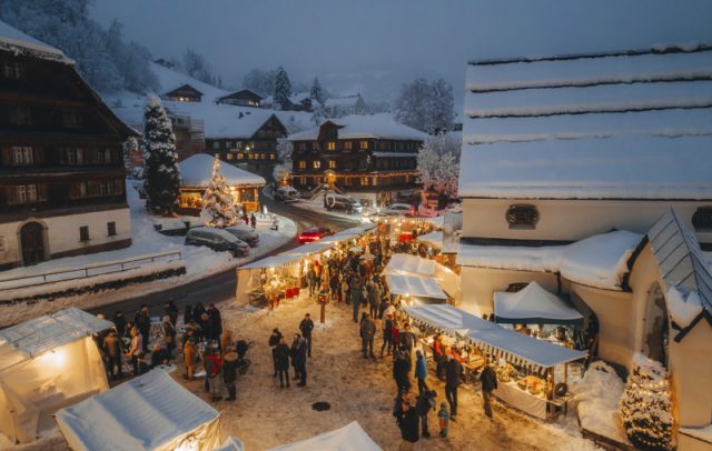 Christmas market in the snow-covered village Schwarzenberg in Bregenzerwald, on the right-hand side the Angelika-Kauffmann-Church,