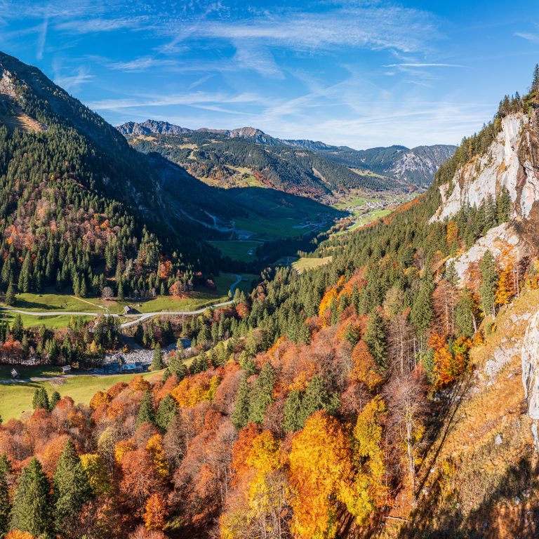 Blick auf das Brandnertal mit herbstlich bunt gefärbtem Wald im Vordergrund