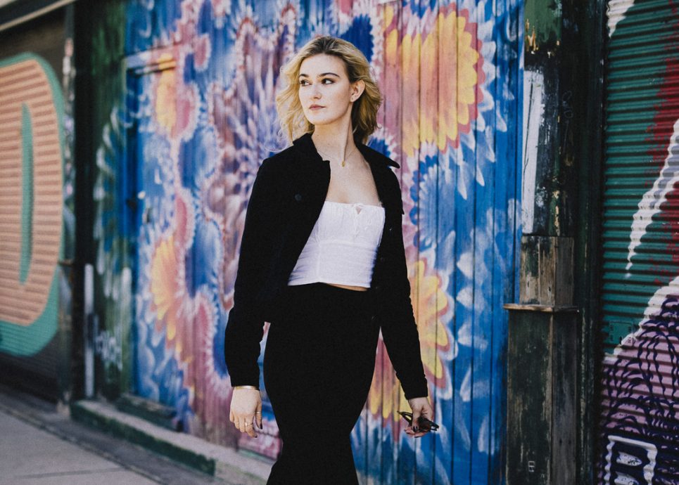 Miriam Kutrowatz spaziert an einer Graffiti-Wand vorbei. Sie ist international gefragte Sopranistin aus dem Burgenland, tritt 2025 bei der :alpenarte in Schwarzenberg auf