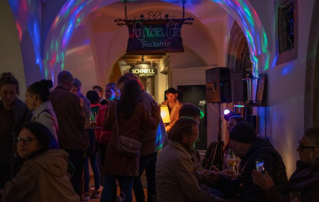 Veranstaltung von Rundklang Feldkrich, Menschen im Laubengang, die einem Musiker zuhören, Kulturveranstaltungen in Vorarlberg