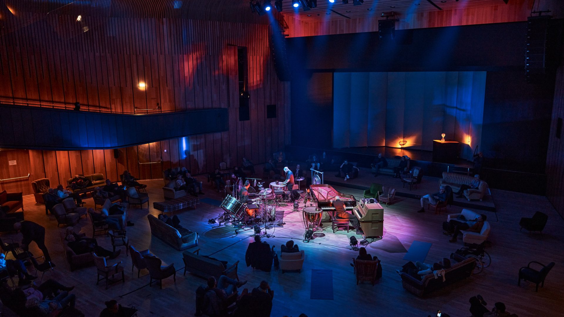 Ein Percussionist spielt inmitten von rund angeordneten Konzertbesuchern, zahlreiche Percussion Instrumente sind auf der Bühnenfläche aufgebaut, cultural events