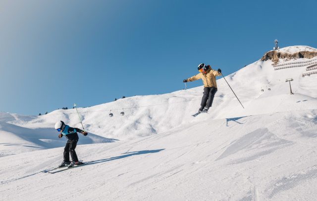 Two skiers in the Diedamskopf ski resort in the Bregenzerwald, one jumps