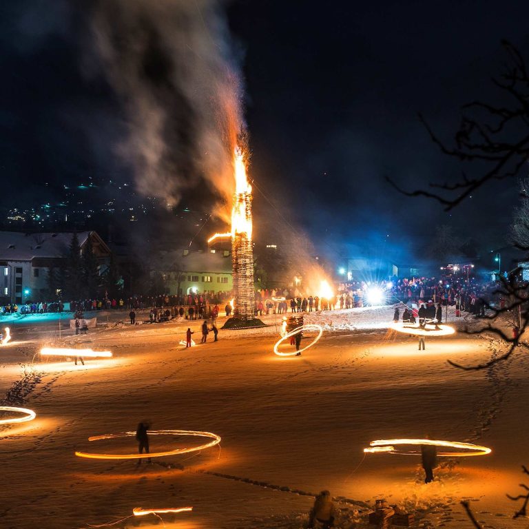 Ein brennender Funken, im Vordergrund Scheibenschläger im Montafon
