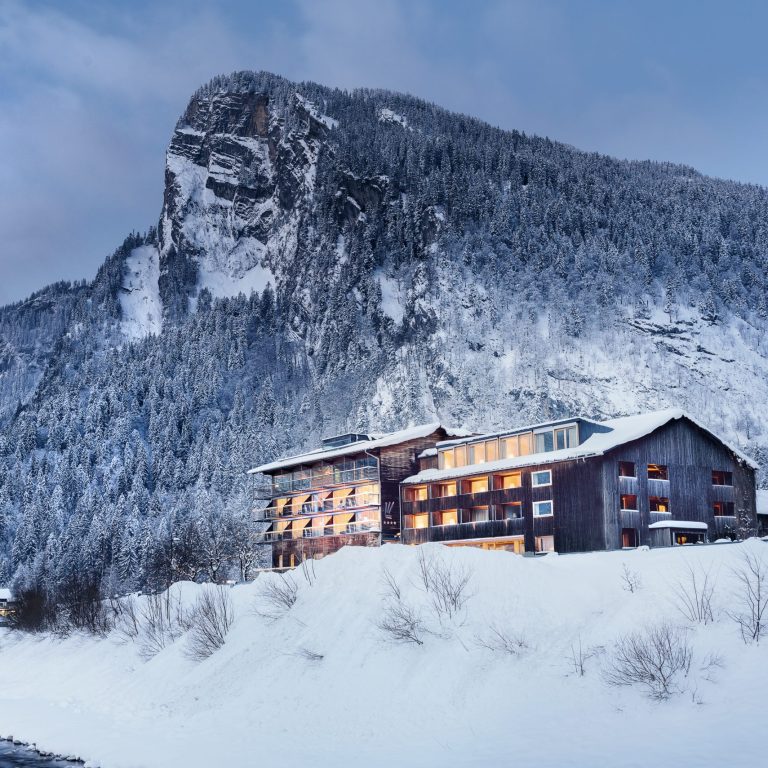 Hotel Krone Au inmitten einer verschneiten Umgebung bei Abendstimmung, Wellnessurlaub Vorarlberg