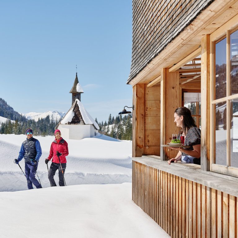 Zwei Winterwanderer im Schnee in Schönenbach, rechts Gasthaus Egender