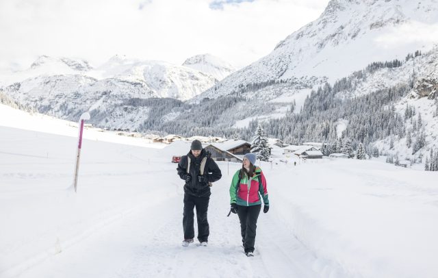 Ein Paar wandern auf einem verschneiten, präparierten Wanderweg am Arlberg in Zug, Sanfter Winter abseits der Pisten in Vorarlberg