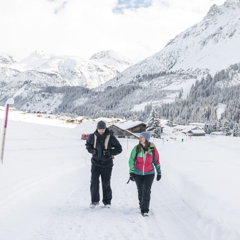 Ein Paar wandern auf einem verschneiten, präparierten Wanderweg am Arlberg in Zug, Sanfter Winter abseits der Pisten in Vorarlberg