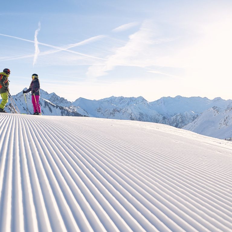 Zwei Skifahrer im Skigebiet Faschina auf frisch präparierten Pisten