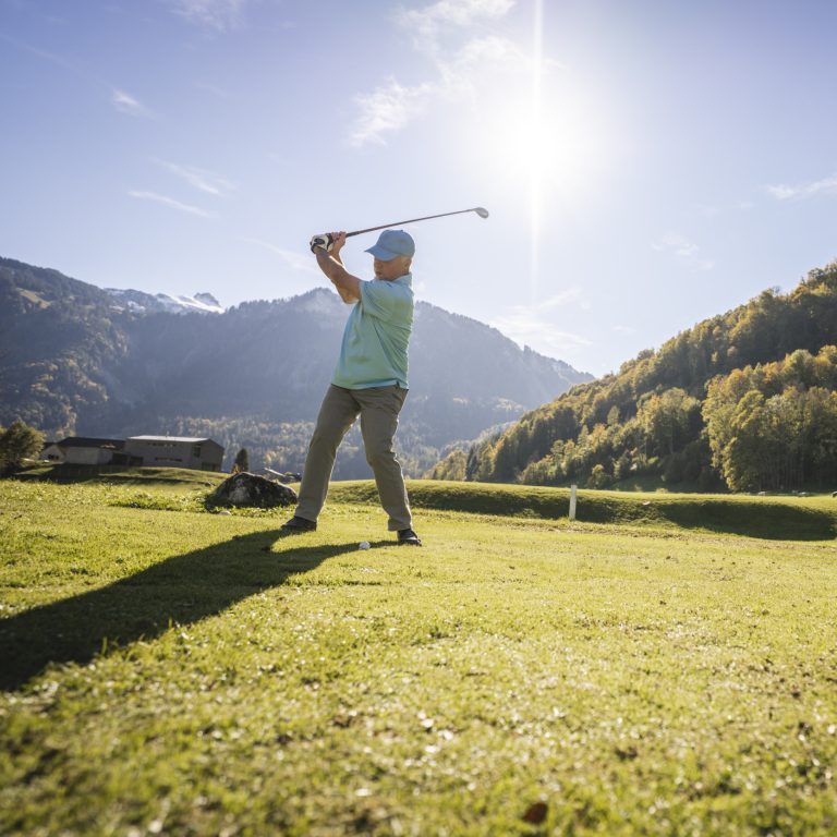 Ein Golfer schwingt seinen Golfschläger am Golf Übungsplatz in Mellau.