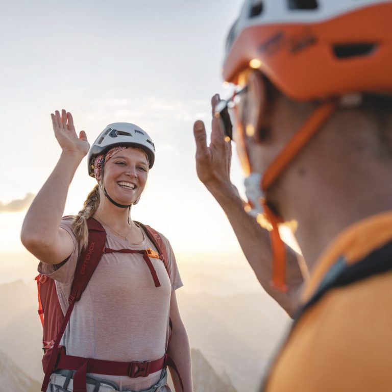 Zwei Bergsteiger freuen sich auf dem Gipfel zu stehen und klatschen High Five.