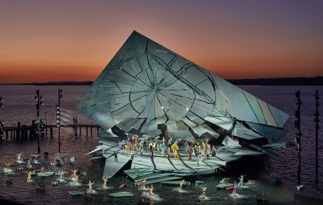 A performance of *La traviata* on the lake stage at the 2026 Bregenz Festival, with Lake Constance and the sunset in the background